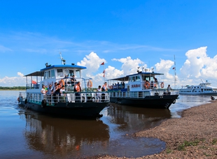 游客乘船游览黑龙江，欣赏界江两岸独特秀丽风光。