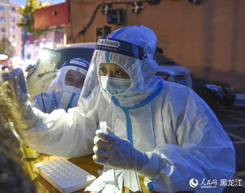 在哈爾濱道外區大有坊街道遼河社區核酸檢測點，工作人員在為居民進行核酸取樣。人民網 蘇靖剛攝