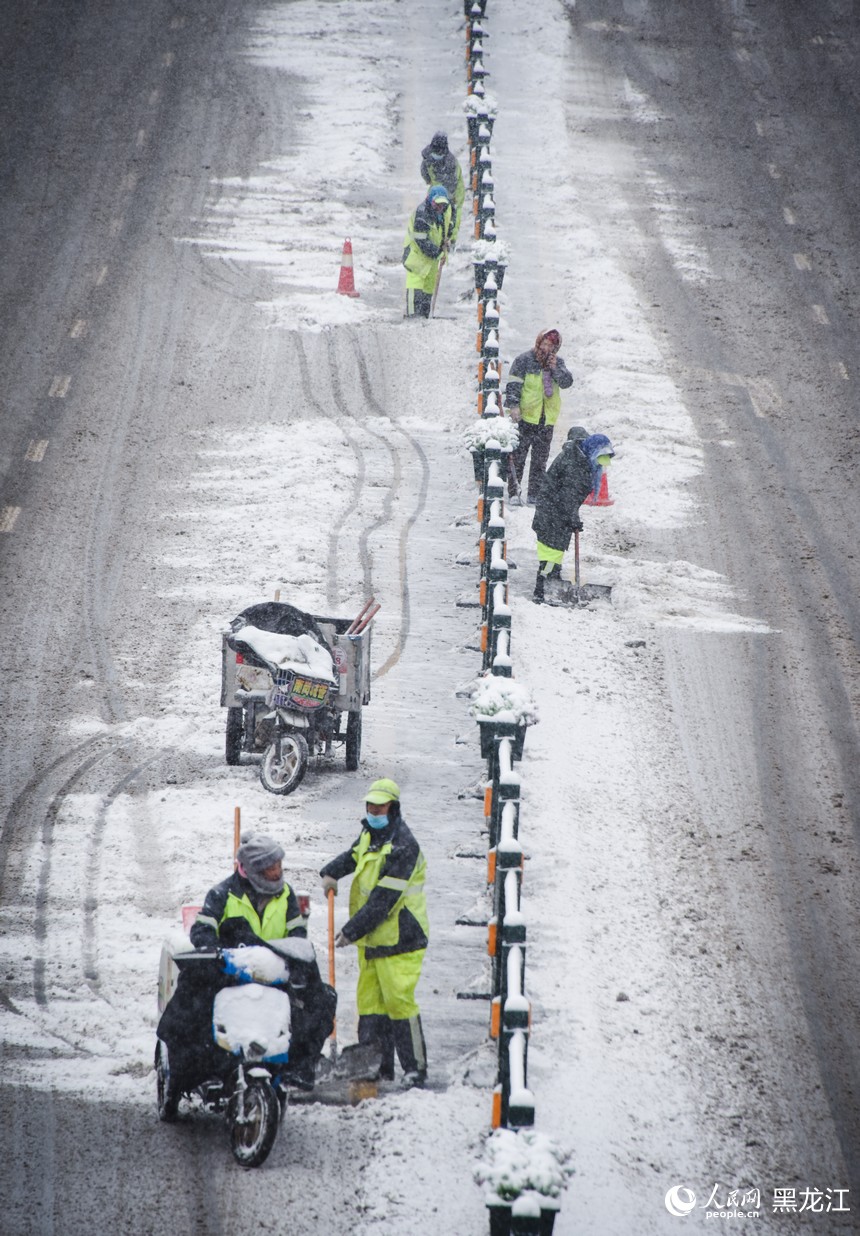 环卫工人正在清理道路积雪，保障路面畅通。人民网记者 苏靖刚摄