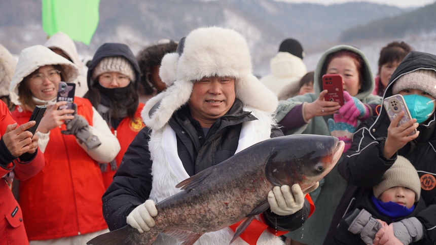 黑龍江海林蓮花湖第二屆冷水魚冬捕節漁民懷抱第一網魚。