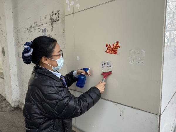 建設銀行鶴崗分行工作人員對牆體上小廣告進行清理。圖片由中國建設銀行黑龍江省分行提供