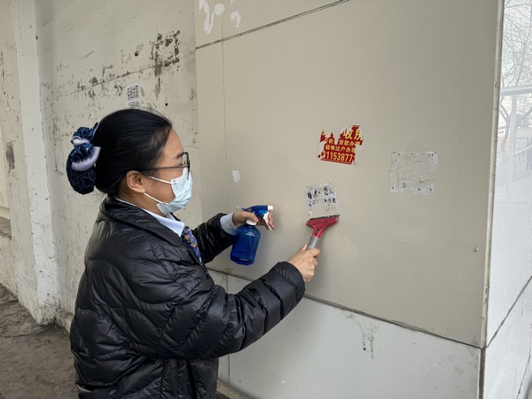 建设银行鹤岗分行工作人员对墙体上小广告进行清理。图片由中国建设银行黑龙江省分行提供