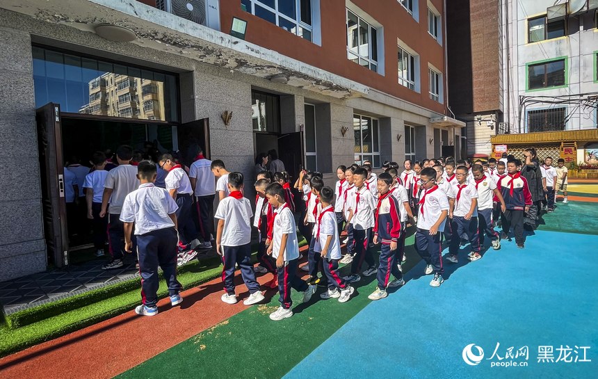 哈尔滨市花园小学的学生们在老师的指导下有序进入学校。人民网记者 张哲鑫摄