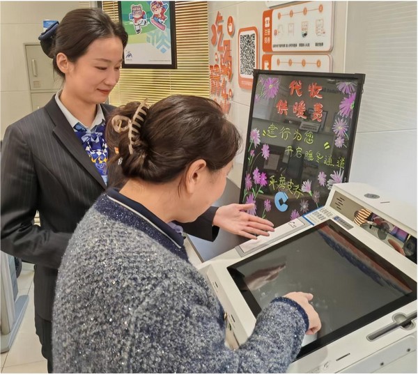 建設銀行哈爾濱平房支行大堂經理隋佳麗指導市民通過網點智慧櫃員機輕鬆繳納熱費。