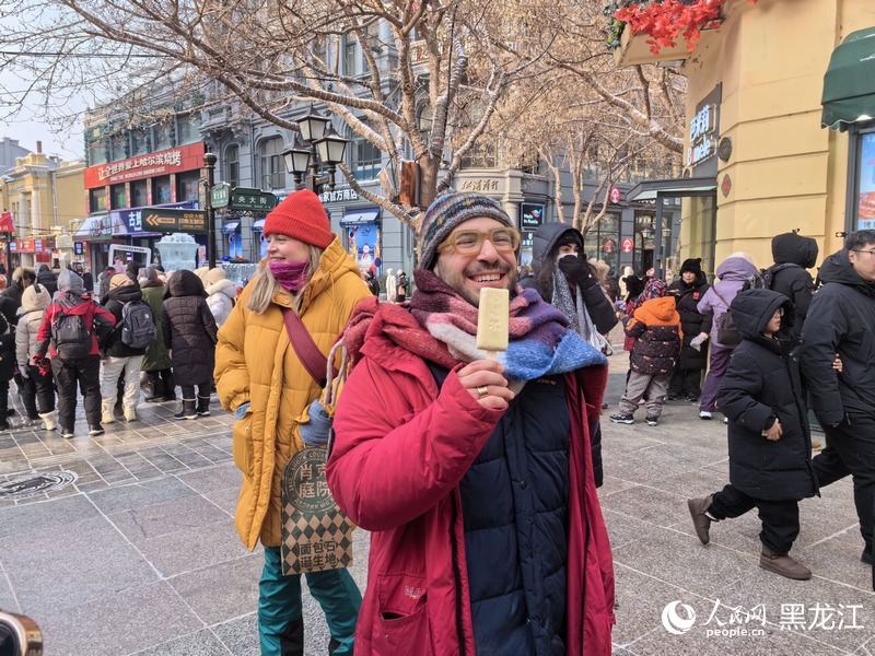 欧洲媒体记者及网红博主考察团成员在哈尔滨中央大街品尝马迭尔冰棍。人民网记者 尚城摄