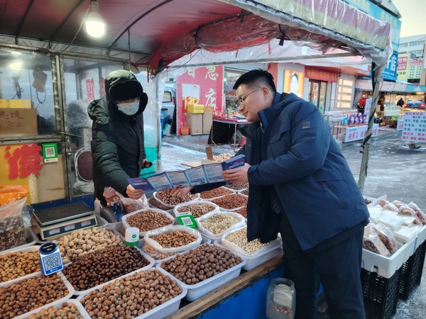 建设银行彩城支行“张富清金融服务队”队员向商户普及反诈知识。中国建设银行黑龙江省分行供图
