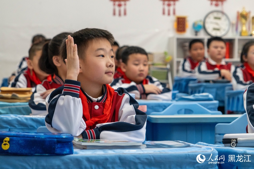 哈尔滨市第十七中学新区学校的课堂上，学生举起右手回应课堂提问。人民网记者 徐成龙摄