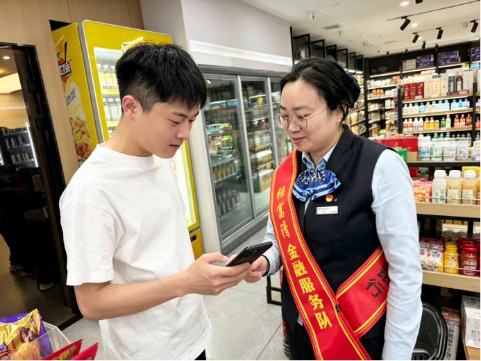 建设银行哈尔滨工大支行“张富清金融服务队”将融资支持与反诈宣教同步送入商户店中。中国建设银行黑龙江省分行供图