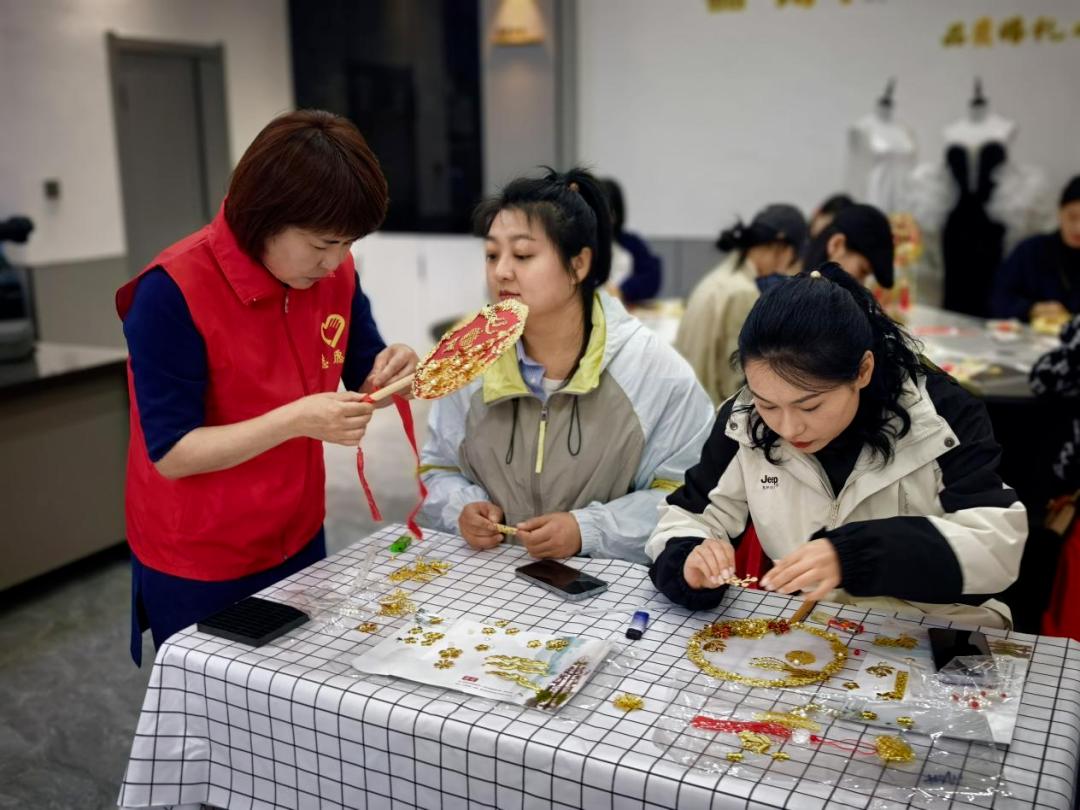 铁西社区志愿者为居民讲解团扇制作工艺。