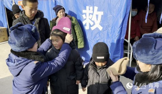 2023年12月21日，青海省海东市消防救援支队的队员们正在为受灾的小朋友穿戴御寒衣物。人民网记者 刘沛然摄